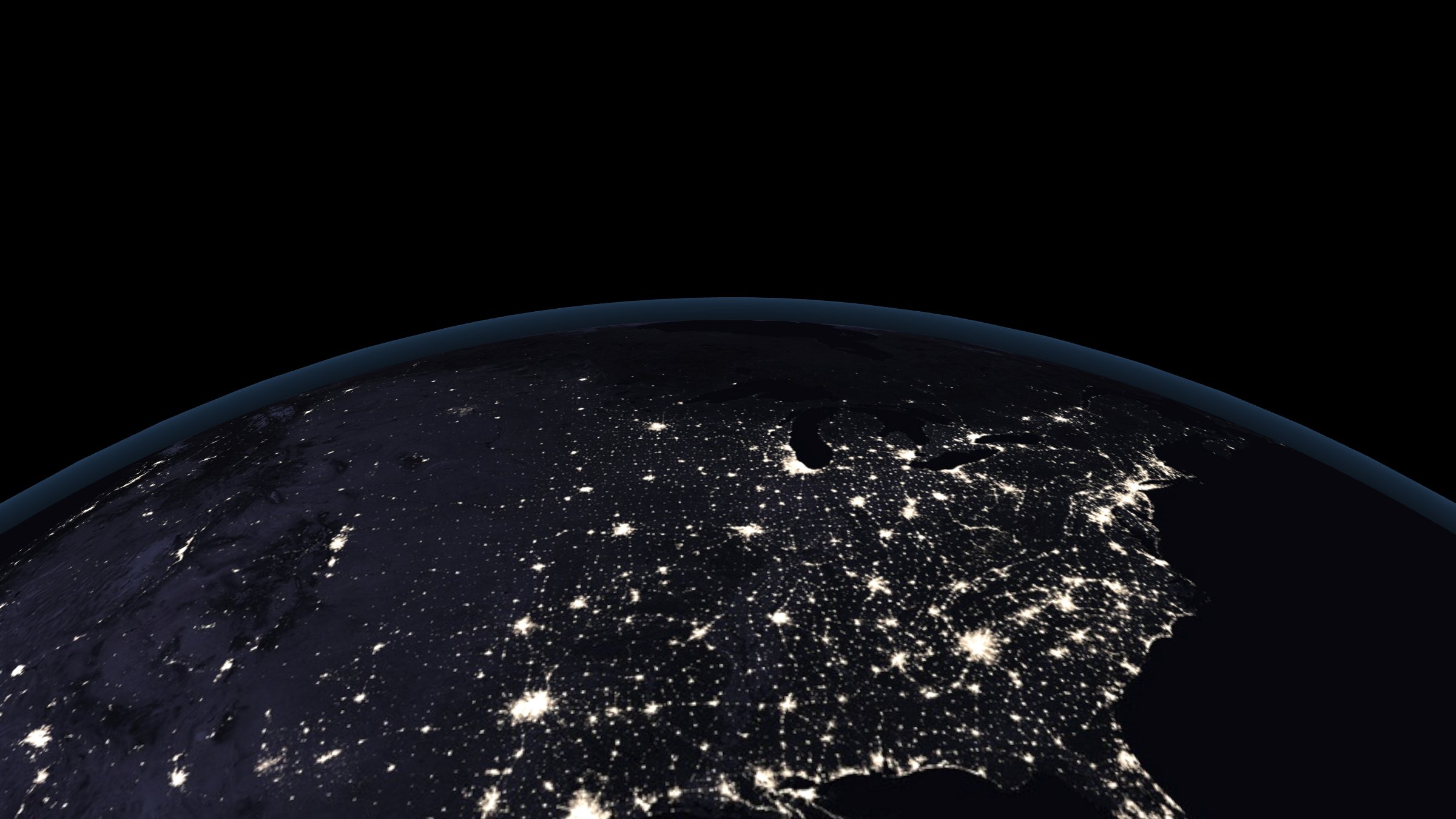 The United States at night from orbit: city lights under a thin line of atmosphere.